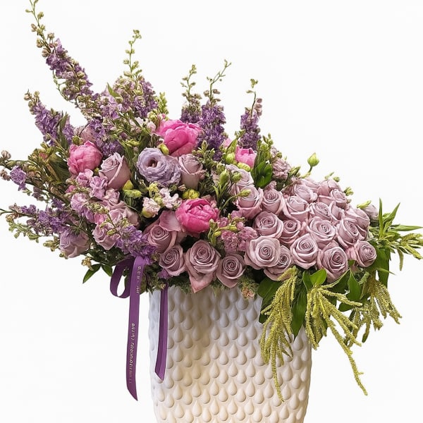 Lavender and pink floral arrangement in a textured cream vase