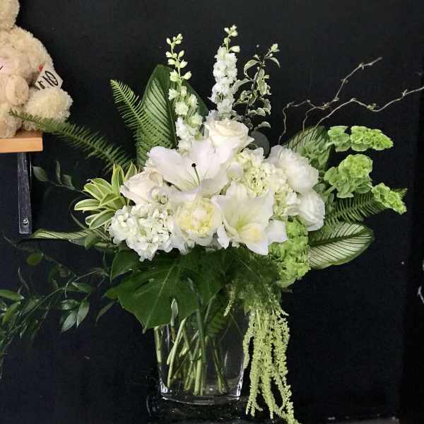 White lilies and hydrangeas arranged in a clear glass vase
