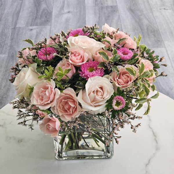 Pink and white rose bouquet in a clear square vase