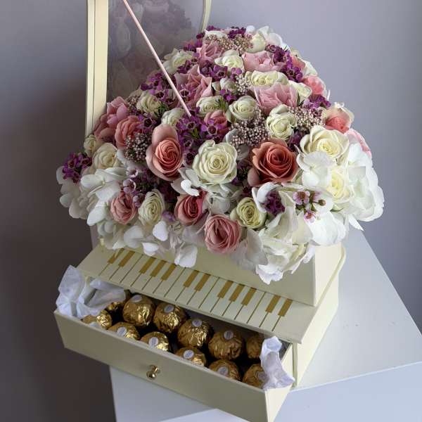 Heart-shaped box of pink and white roses with chocolates in a drawer and a purple butterfly decoration.