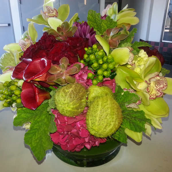 Colorful floral arrangement in a glass bowl with orchids and hydrangeas