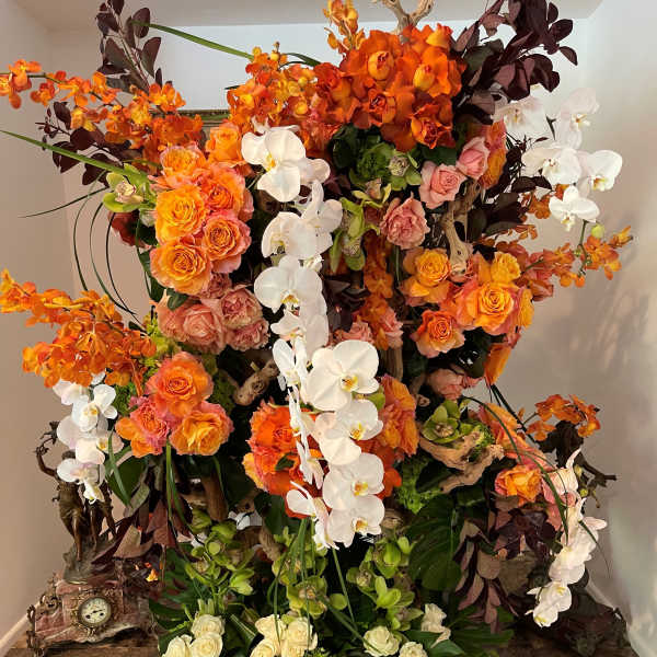 Large floral arrangement with orange roses and white orchids