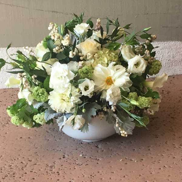 White floral arrangement in a round white bowl vase