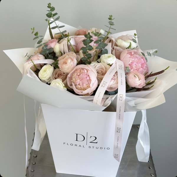 Blush pink and white bouquet with ribbon in a white gift bag