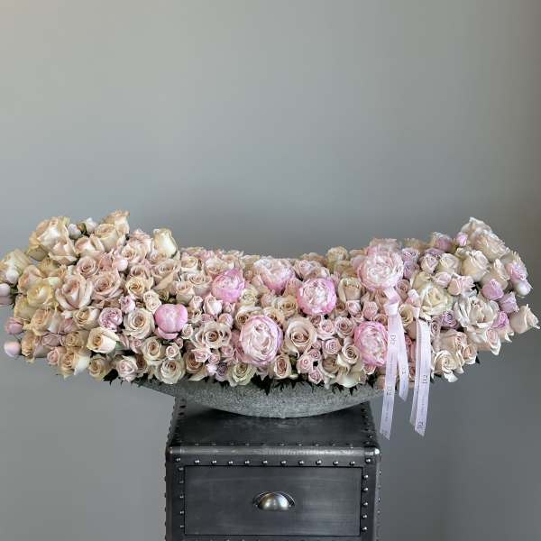 Low arrangement of pale pink and cream roses in a gray bowl