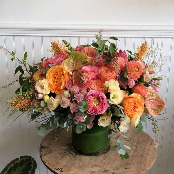 Large mixed bouquet in a green vase with pink, peach, and orange flowers