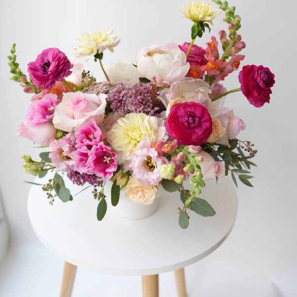 Mixed bouquet of pink, white, and yellow flowers in a white vase