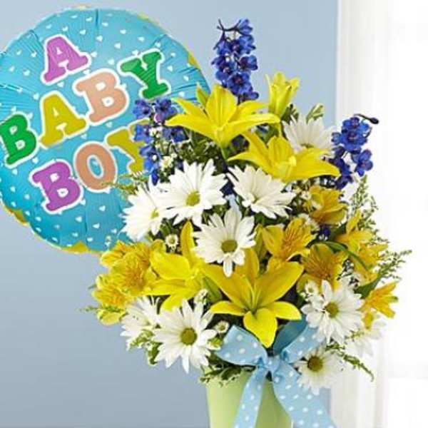 Yellow lilies and white daisies in a green pot with blue polka dot bow and baby boy balloon