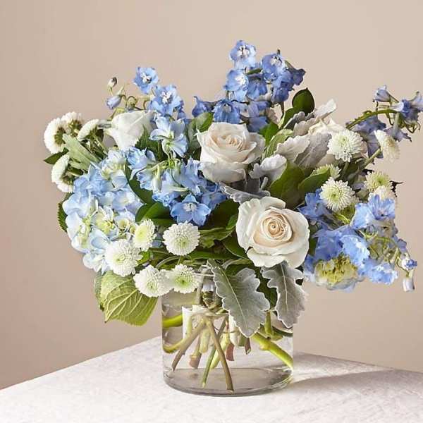 Blue and white flowers arranged in a clear glass vase