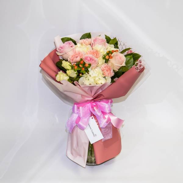 Pink and white bouquet of roses and carnations in wrapping with a ribbon