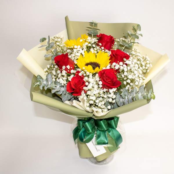 Bouquet of red roses and yellow sunflowers wrapped in green paper