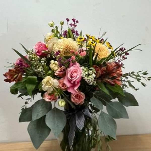 Mixed bouquet of pink and yellow flowers in a glass vase