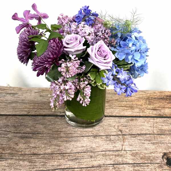 Purple and blue flowers arranged in a glass vase