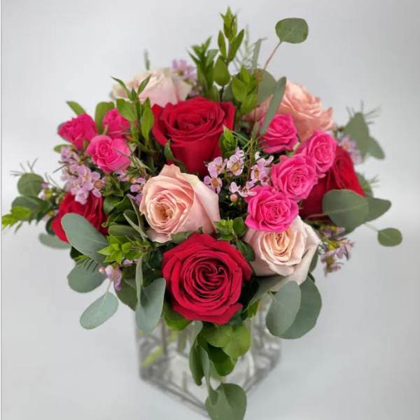 Bouquet of red, pink, and blush roses in a clear glass vase