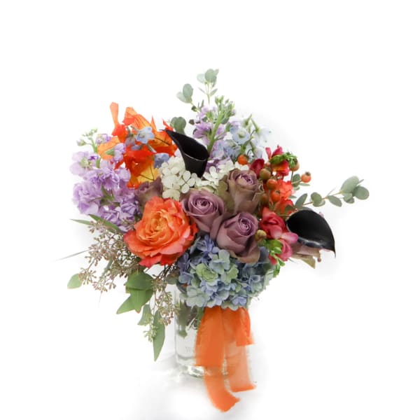 Colorful bouquet of roses, hydrangeas, and mixed blooms in a glass vase