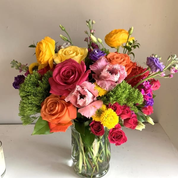 Colorful mixed bouquet of roses and other blooms in a clear glass vase
