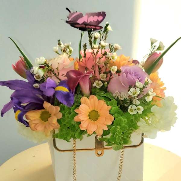 Colorful flower arrangement in a white handbag-shaped container