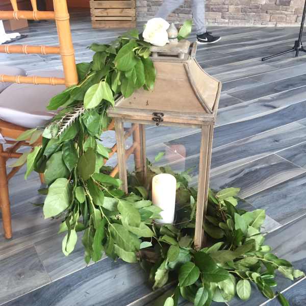 Green garland draped around a wooden lantern with white candles