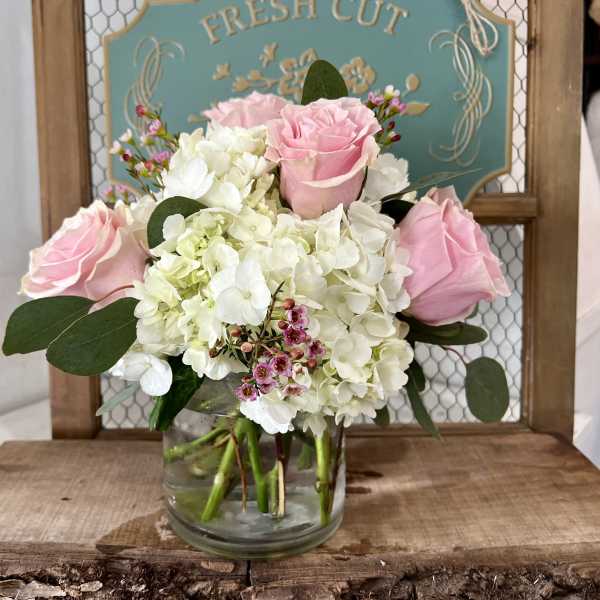 Pink roses and white hydrangeas in a clear glass vase