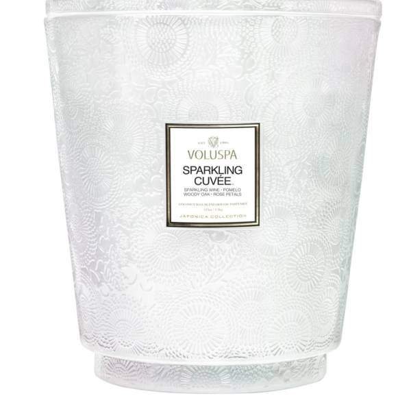 White patterned candle in a glass vessel with a label