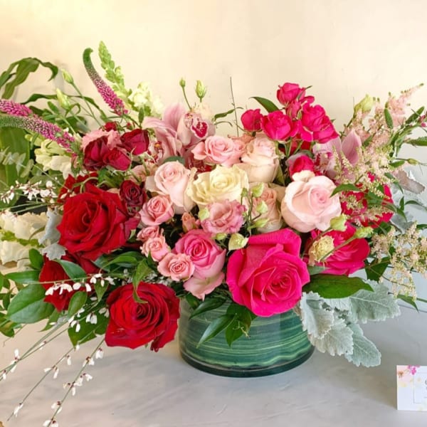 Large bouquet of pink and red roses in a green glass vase