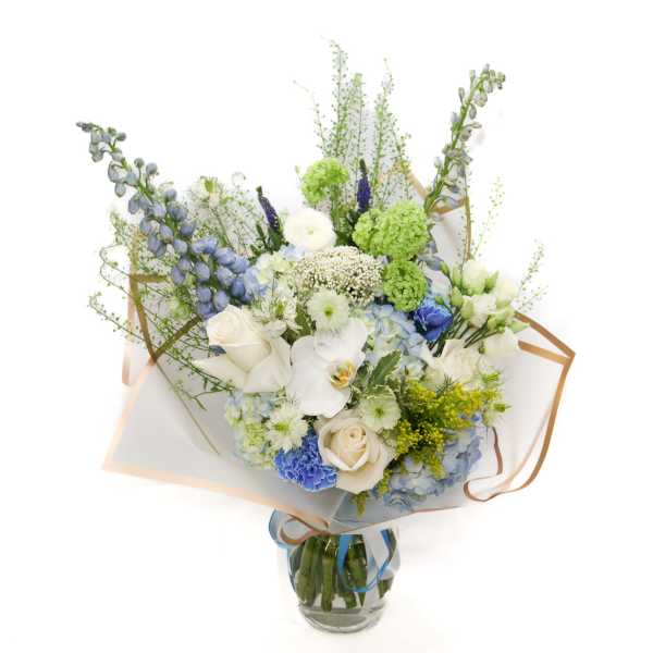 Bouquet of white, blue, and green flowers in a glass vase