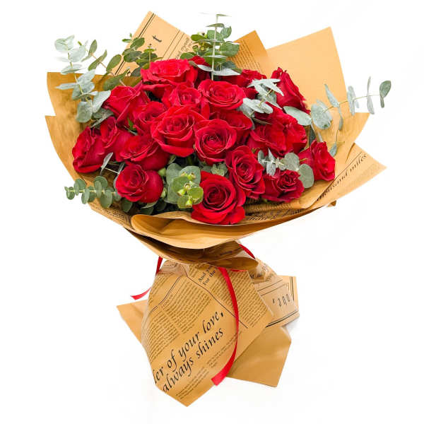 Bouquet of red roses wrapped in tan paper with eucalyptus