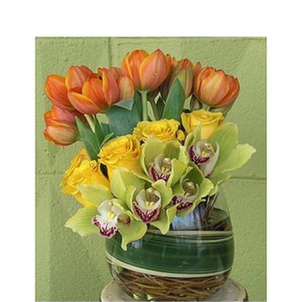 Orange tulips, yellow roses, and green orchids in a glass vase