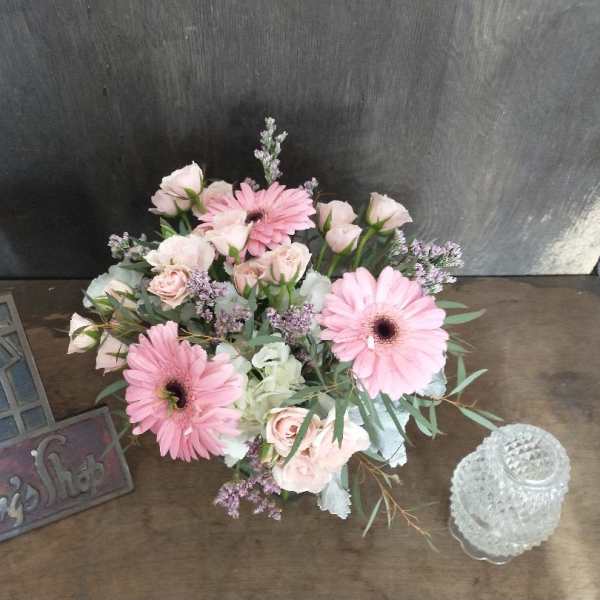 Pink gerbera daisies and pale roses arranged on a table
