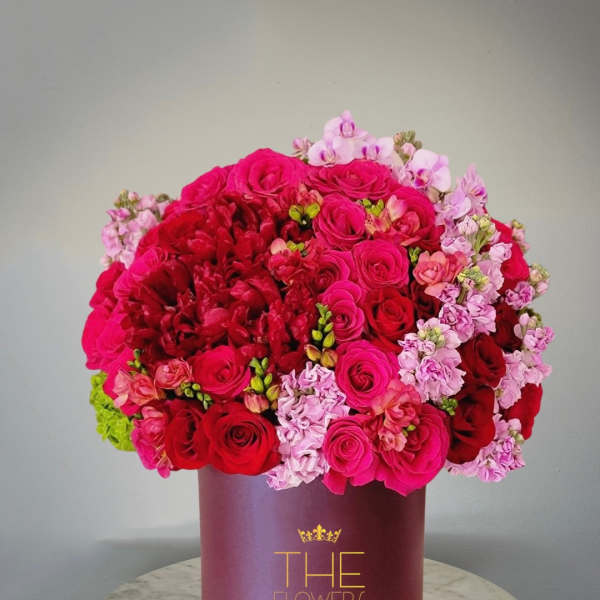 Pink and red roses with light pink blooms in a burgundy hatbox