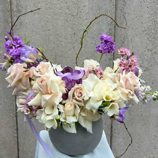 Bouquet of cream and lavender flowers in a gray vase