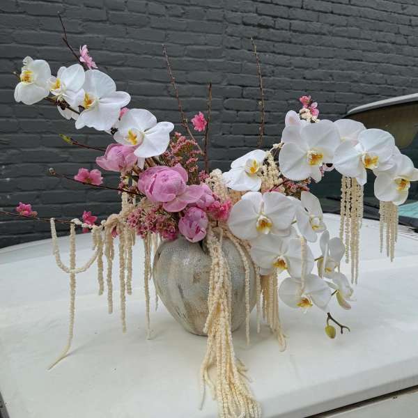 Pink and white orchid arrangement in a ceramic vase