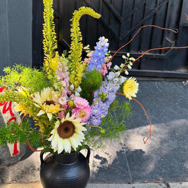 Tall mixed bouquet in a black vase with sunflowers and pastel blooms