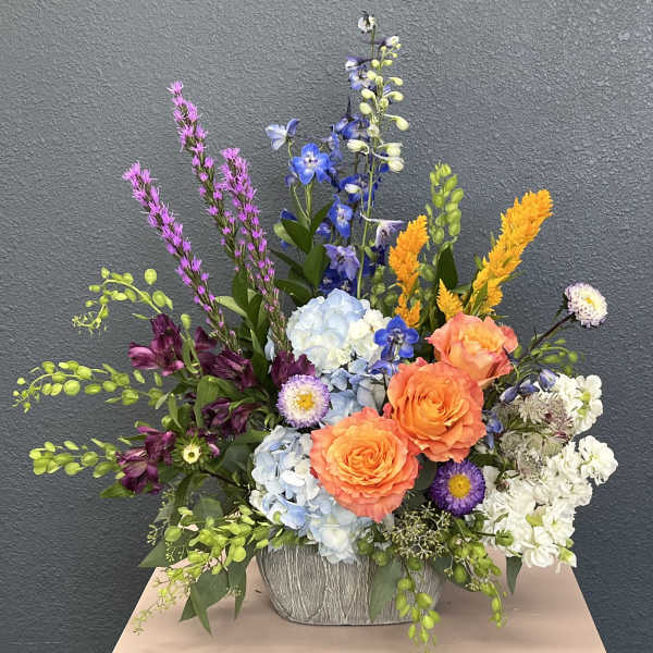 Colorful mixed flower arrangement in a textured gray container