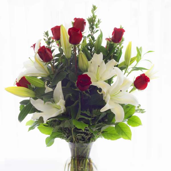 Red roses and white lilies arranged in a clear glass vase