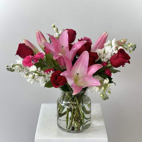 Pink lilies and red roses in a clear glass vase