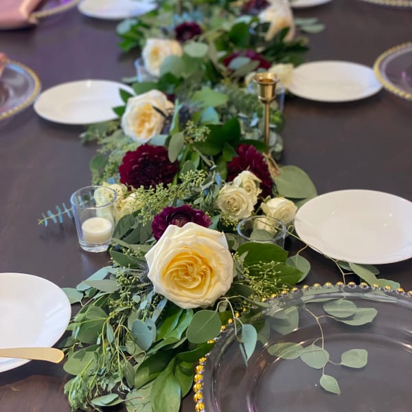 Long floral table runner with cream and burgundy roses on a dining table