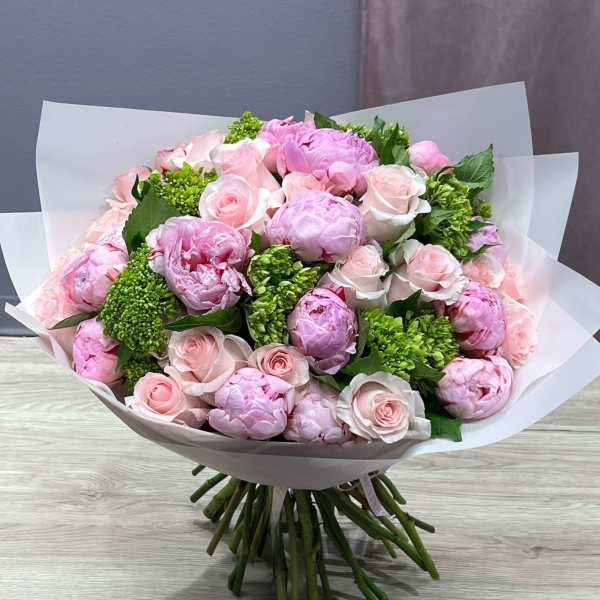 Bouquet of pink peonies and pale pink roses wrapped in white paper