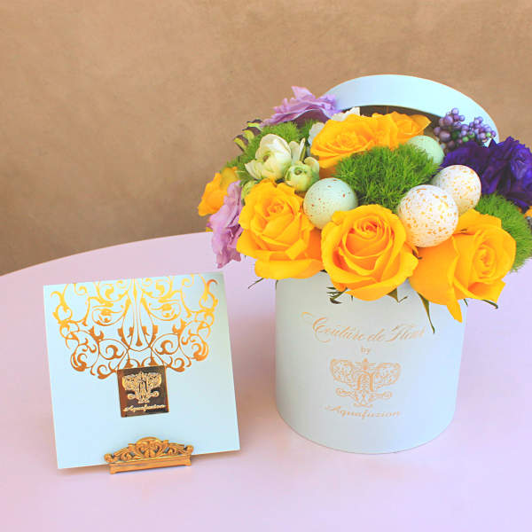 Yellow roses and purple flowers in a white hat box with decorative eggs