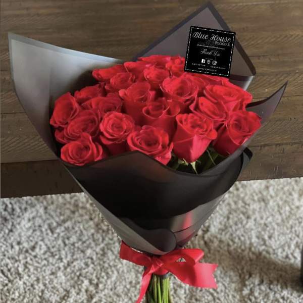 Bouquet of red roses wrapped in black paper with a red ribbon