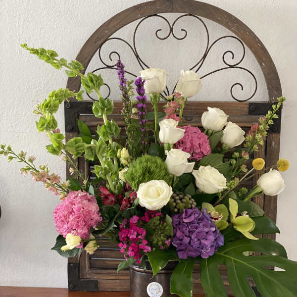 Mixed bouquet with white roses and pink and purple blooms in a metal bucket