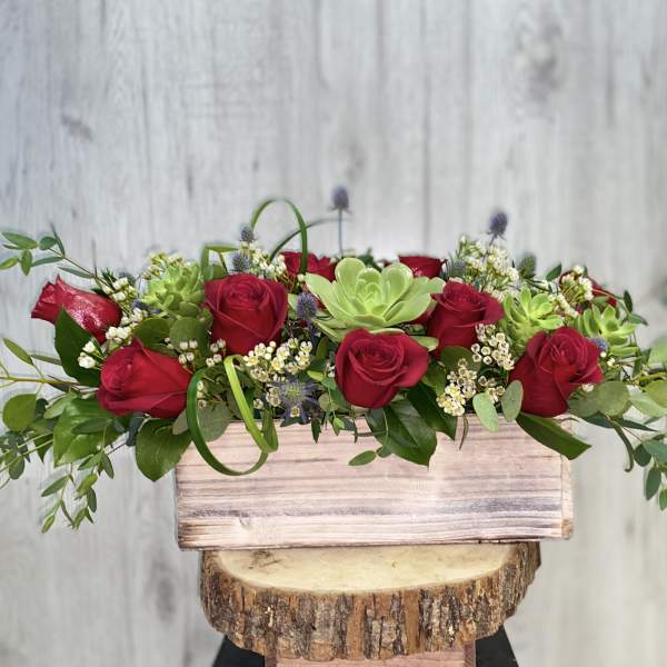 Red roses and succulents in a rustic wooden box