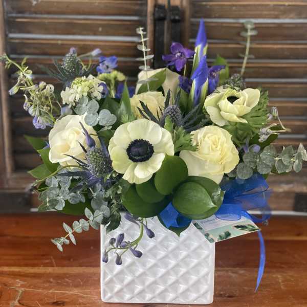 Bouquet of cream and purple flowers in a white textured vase