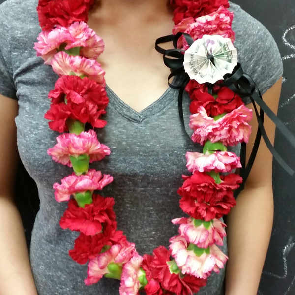 Woman wearing a lei of red and pink carnations with a black ribbon bow