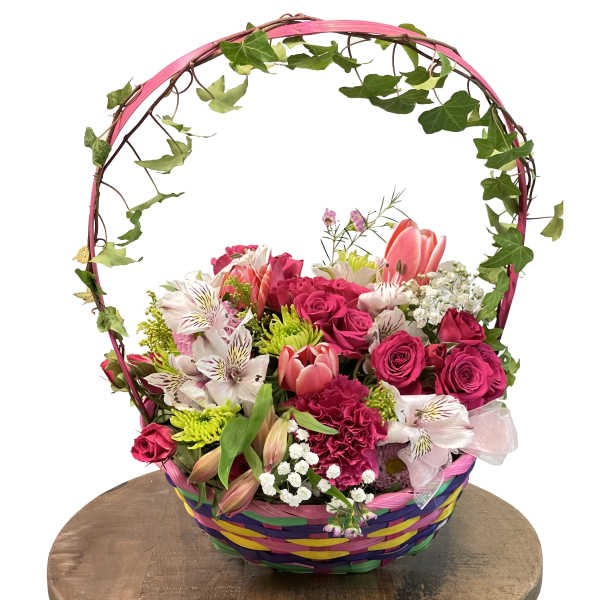 Basket arrangement of pink roses, tulips, and mixed flowers with an ivy handle