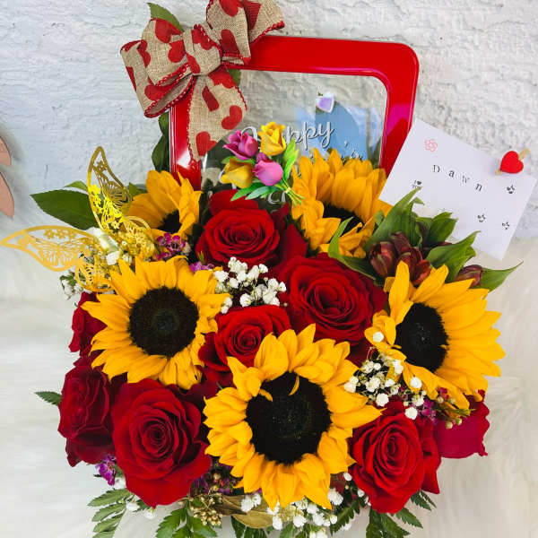 Bouquet of red roses and yellow sunflowers in a red gift box