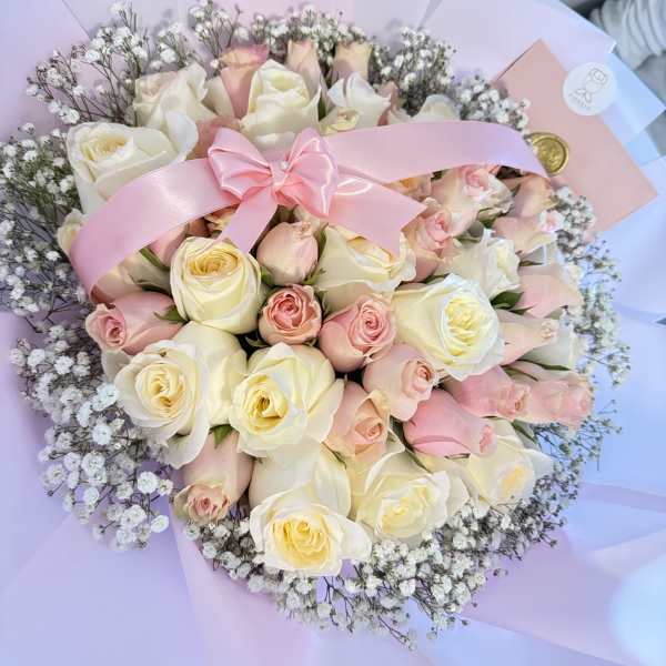 Bouquet of cream and blush roses with a pink ribbon