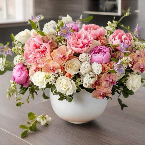 Pink and white floral arrangement in a white bowl vase