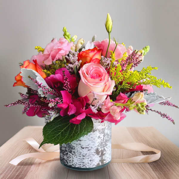 Pink and orange mixed bouquet in a white patterned vase