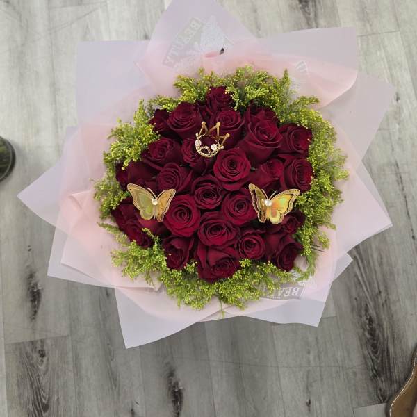 Bouquet of deep red roses with pink wrapping and butterfly picks